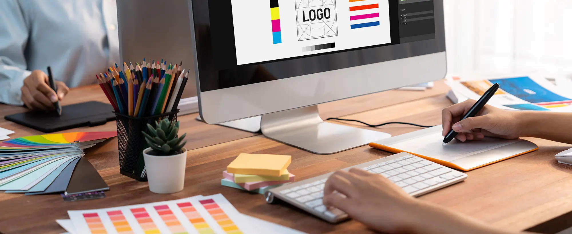 aaAdobeStock_592513372 Ein Mann sitzt vor dem Computer und macht Grafikdesign.